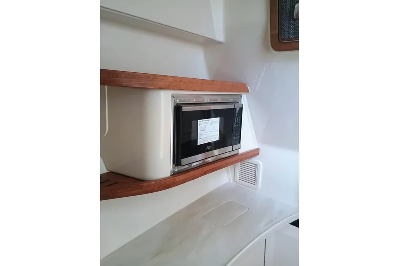 375-307 Brokerage Ron Yacht Photos Pics 2025 Grady-White Freedom 375 interior with built-in microwave and wooden accents.