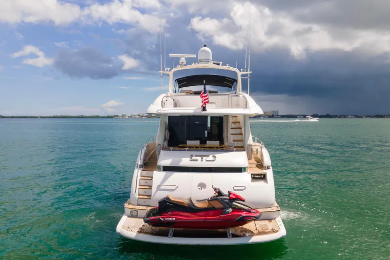 Living The Dream Yacht Photos Pics Luxury 2008 Lazzara 84 Open Bridge yacht with jet ski on calm waters.