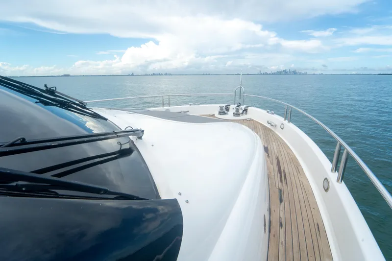Living The Dream Yacht Photos Pics 2008 Lazzara 84 Open Bridge yacht cruising on calm waters with city skyline in background.