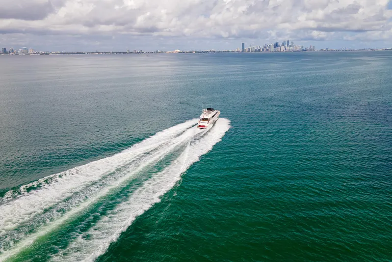 Living The Dream Yacht Photos Pics Lazzara 84 Open Bridge yacht cruising on ocean with city skyline in background, 2008 model.