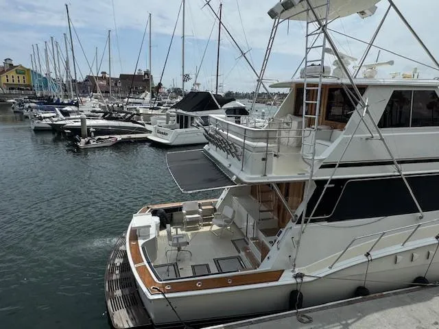 Andiamo Yacht Photos Pics 1982 Hatteras Enclosed Flybridge yacht docked in a marina with sailboats.