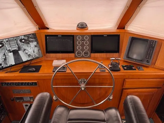 Andiamo Yacht Photos Pics 1982 Hatteras Enclosed Flybridge helm with steering wheel, navigation screens, and control panels.