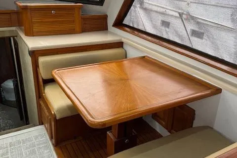 Andiamo Yacht Photos Pics 1982 Hatteras Enclosed Flybridge interior with wooden table and seating.