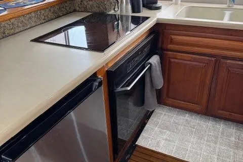 Andiamo Yacht Photos Pics 1982 Hatteras Enclosed Flybridge kitchen with stove, dishwasher, and wooden cabinets.