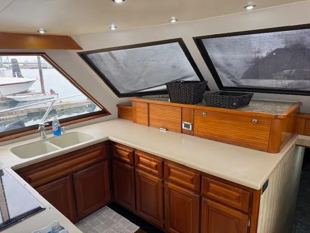 Andiamo Yacht Photos Pics 1982 Hatteras Enclosed Flybridge kitchen with wooden cabinets and large windows.