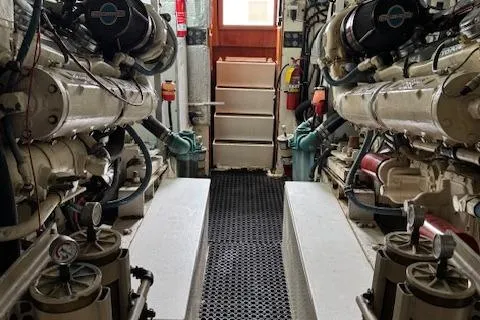 Andiamo Yacht Photos Pics Engine room of a 1982 Hatteras Enclosed Flybridge yacht, showcasing dual engines and equipment.