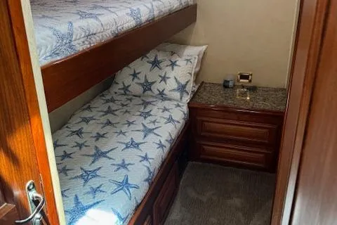 Andiamo Yacht Photos Pics 1982 Hatteras Enclosed Flybridge cabin with starfish-themed bedding and wooden cabinetry.