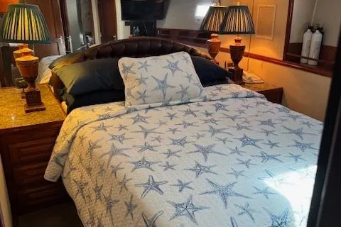 Andiamo Yacht Photos Pics 1982 Hatteras Enclosed Flybridge bedroom with starfish-patterned bedding and elegant lamps.