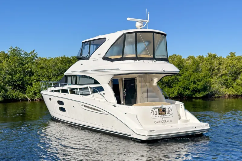  Yacht Photos Pics 2015 Meridian 441 Sedan yacht cruising on calm waters near lush greenery.