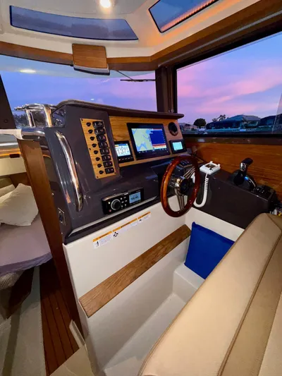  Yacht Photos Pics 2022 Ranger Tugs R-27 helm with navigation system and wooden steering wheel at sunset.