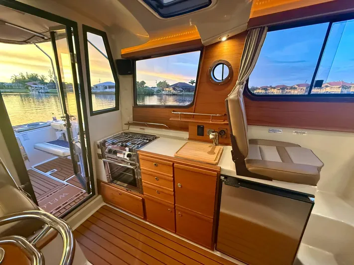  Yacht Photos Pics Interior of 2022 Ranger Tugs R-27 boat with kitchen and seating area at sunset.