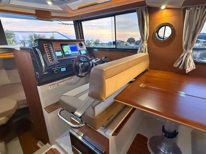  Yacht Photos Pics 2022 Ranger Tugs R-27 interior with helm, navigation screens, and wooden dining area.