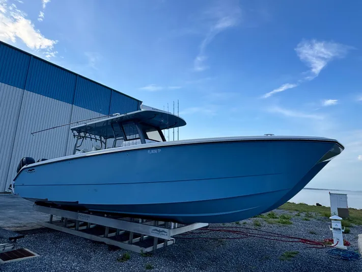  Yacht Photos Pics 2022 Invincible 40 Catamaran in blue, docked near a warehouse under a clear sky.