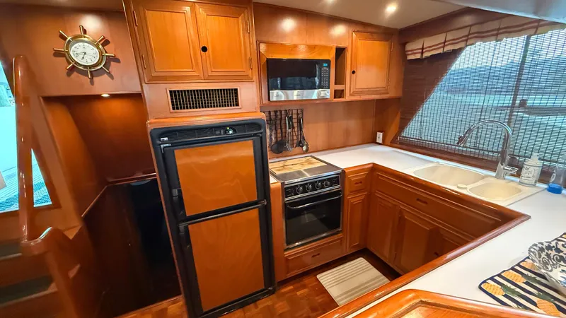 Destination Yacht Photos Pics 1995 Ocean Alexander 546 yacht kitchen with wood cabinetry, stove, fridge, and large window.