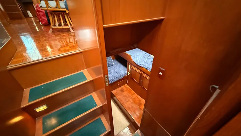 Destination Yacht Photos Pics Interior of 1995 Ocean Alexander 546 yacht, featuring wooden stairs and cozy cabin with blue bedding.