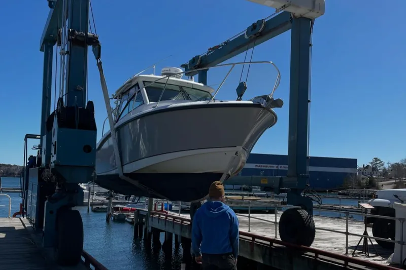 Fortunate Son Yacht Photos Pics 2013 Boston Whaler 315 Conquest boat being lifted by a crane at a marina.