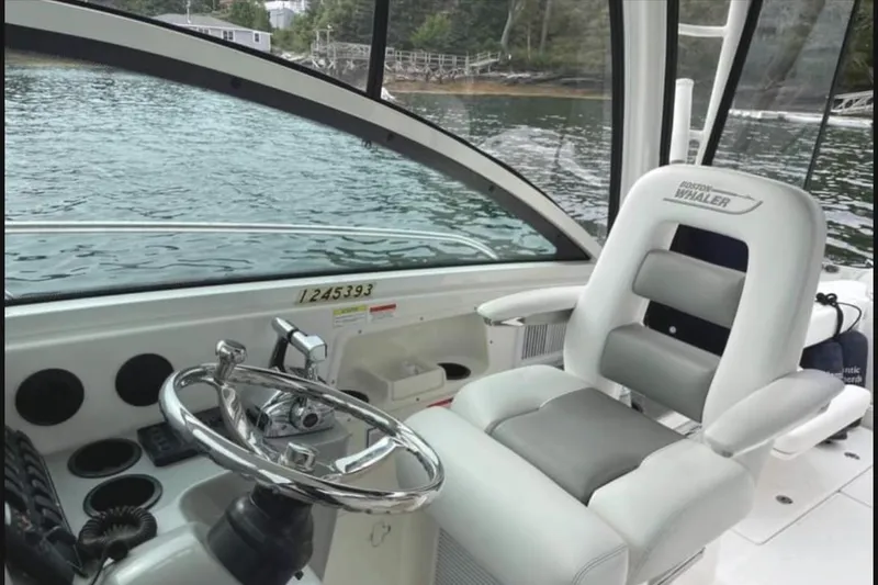 Fortunate Son Yacht Photos Pics 2013 Boston Whaler 315 Conquest helm with steering wheel and captain's chair, overlooking water.