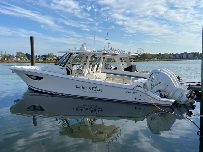  Yacht Photos Pics 2022 Pursuit 378S boat docked on calm water under a blue sky.