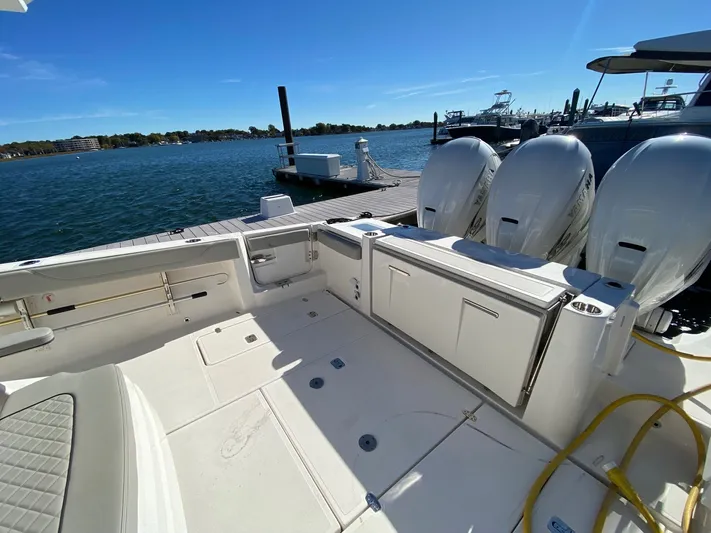  Yacht Photos Pics 2022 Pursuit 378S boat with triple engines docked by a serene waterfront.
