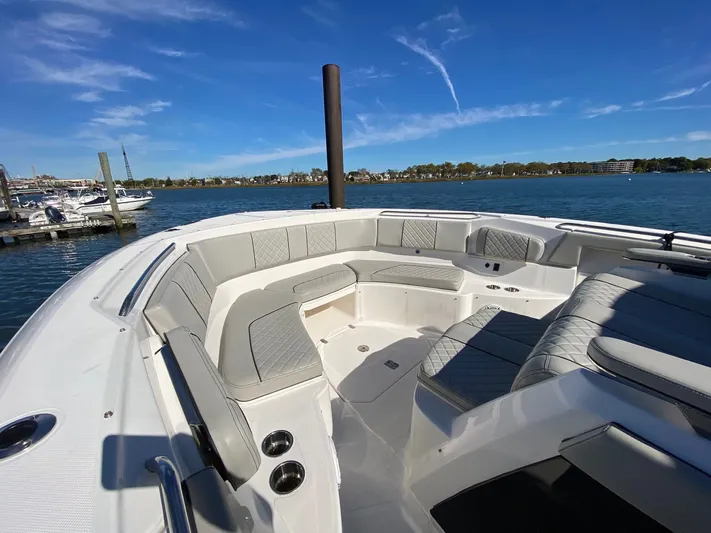  Yacht Photos Pics 2022 Pursuit 378S boat with spacious seating, docked by a scenic waterfront.