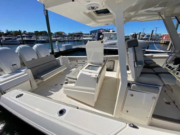  Yacht Photos Pics 2022 Pursuit 378S boat interior with seating, storage, and outboard motors at a marina.