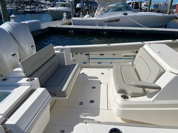  Yacht Photos Pics 2022 Pursuit 378S boat interior with cushioned seating at a marina.