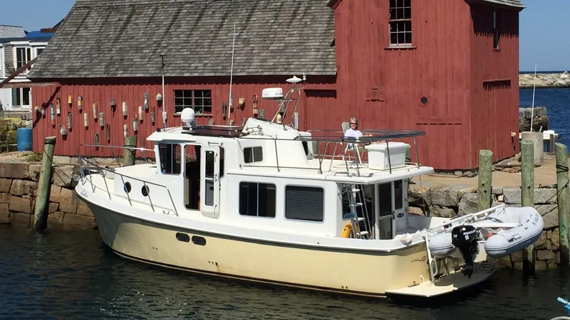 Leto Yacht Photos Pics 2001 American Tug 34 docked by a rustic red building.
