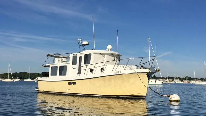 Leto Yacht Photos Pics American Tug 34, 2001 model, anchored in a serene harbor under a clear blue sky.