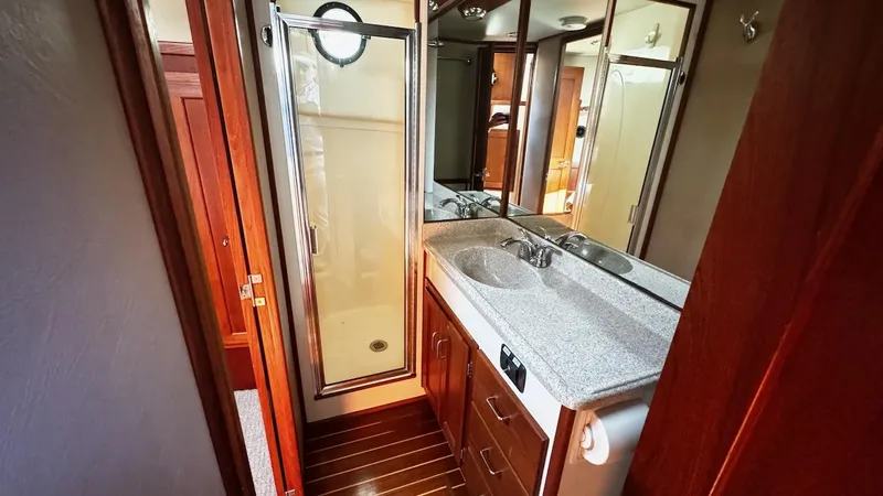 Leto Yacht Photos Pics 2001 American Tug 34 bathroom with shower, sink, and wooden cabinetry.