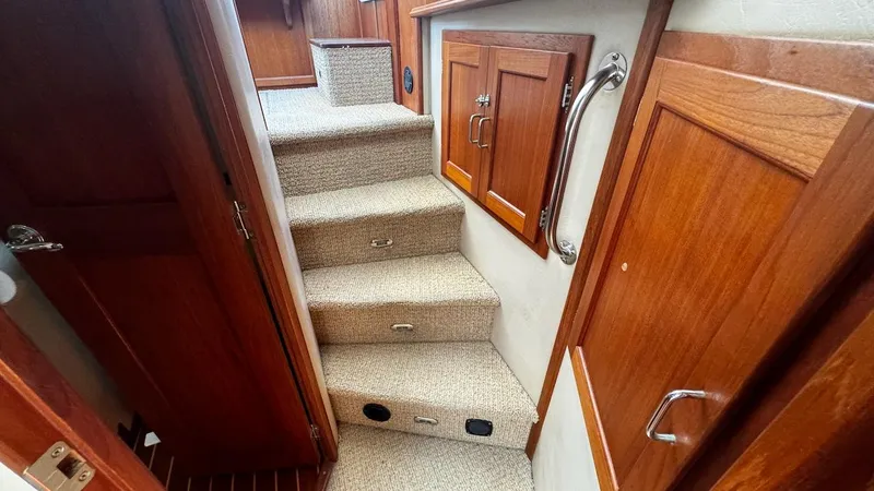 Leto Yacht Photos Pics Interior stairs of 2001 American Tug 34, featuring wooden cabinetry and carpeted steps.