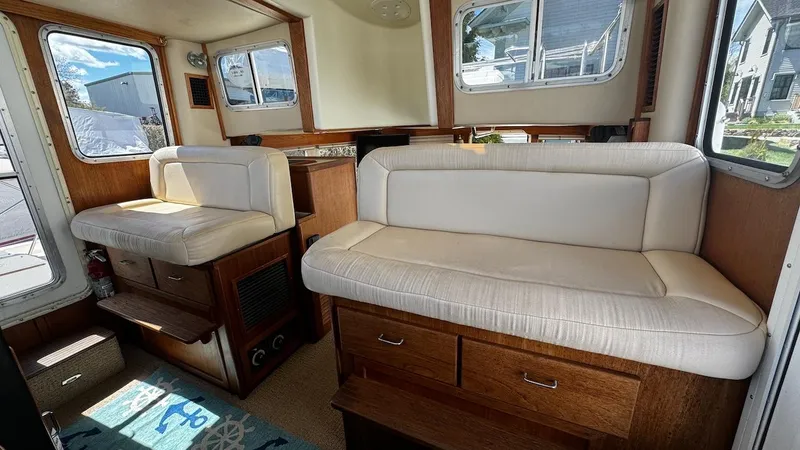 Leto Yacht Photos Pics Interior of 2001 American Tug 34 with white cushioned seating and wooden accents.