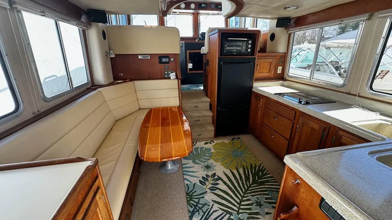 Leto Yacht Photos Pics Interior of 2001 American Tug 34, featuring a cozy seating area, kitchen, and wooden accents.