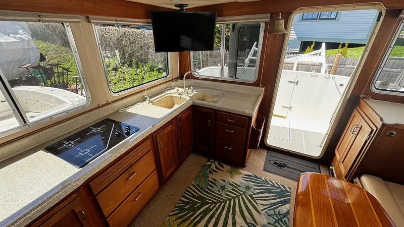 Leto Yacht Photos Pics Interior of 2001 American Tug 34 with kitchen, sink, stove, and TV.