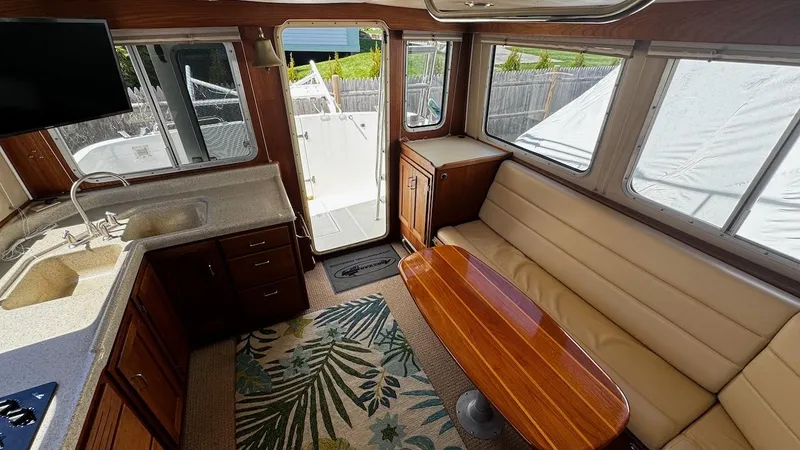 Leto Yacht Photos Pics Interior of 2001 American Tug 34 with kitchen, seating, and wooden table.