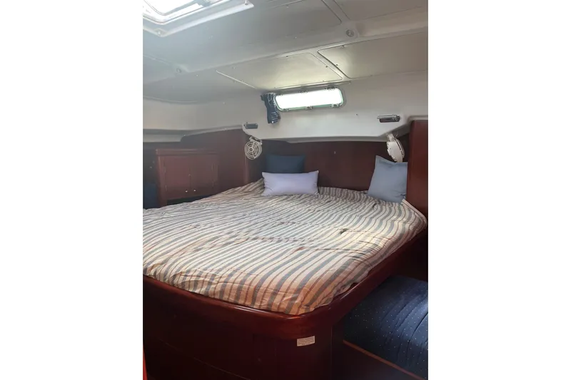  Yacht Photos Pics Cozy cabin interior of 2003 Beneteau Oceanis 42CC with striped bedding and pillows.
