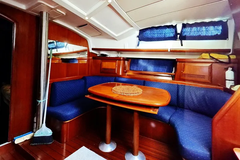 Sea No Evil Yacht Photos Pics Interior of 2003 Beneteau Oceanis 42CC yacht with wooden dining area and blue seating.