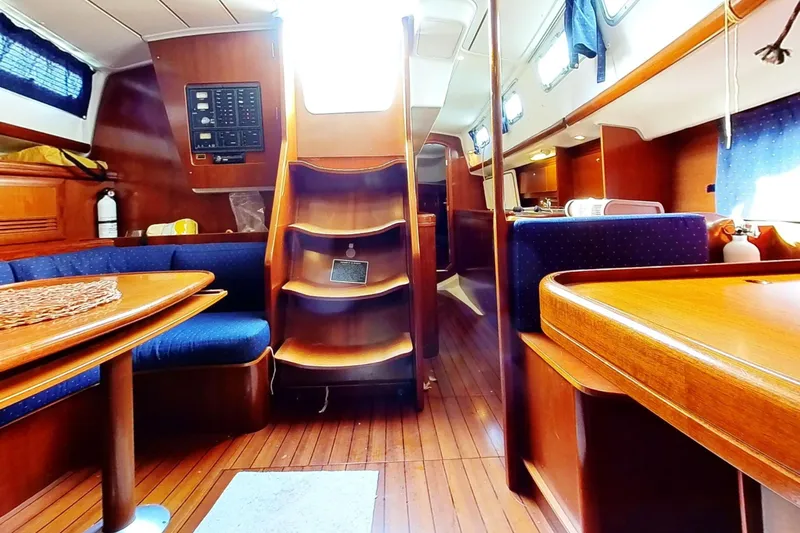 Sea No Evil Yacht Photos Pics Interior of 2003 Beneteau Oceanis 42CC sailboat with wooden furnishings and blue seating.