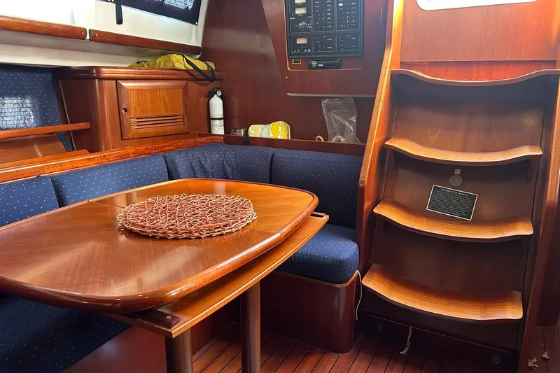 Sea No Evil Yacht Photos Pics Interior of 2003 Beneteau Oceanis 42CC yacht with wooden table and blue seating.