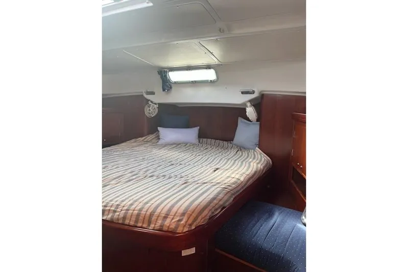 Sea No Evil Yacht Photos Pics Cozy cabin interior of 2003 Beneteau Oceanis 42CC with striped bedding and wooden furnishings.