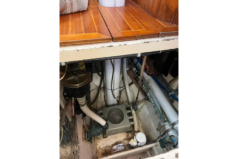 Wind Star Yacht Photos Pics Engine compartment of a 1986 Liberty 49 boat, showing mechanical components and wooden flooring.