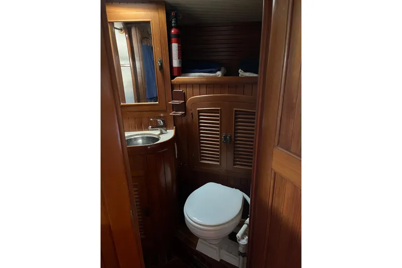 Wind Star Yacht Photos Pics Compact wooden bathroom interior on a 1986 Liberty 49 boat, featuring a sink and toilet.