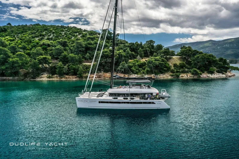 Duolife Yacht Yacht Photos Pics Luxurious 2019 Lagoon 620 catamaran sailing near a lush, green island.