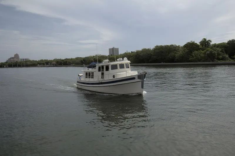 Hercules Yacht Photos Pics Nordic Tug 42 Millennium 2000 cruising on a calm river with lush greenery.