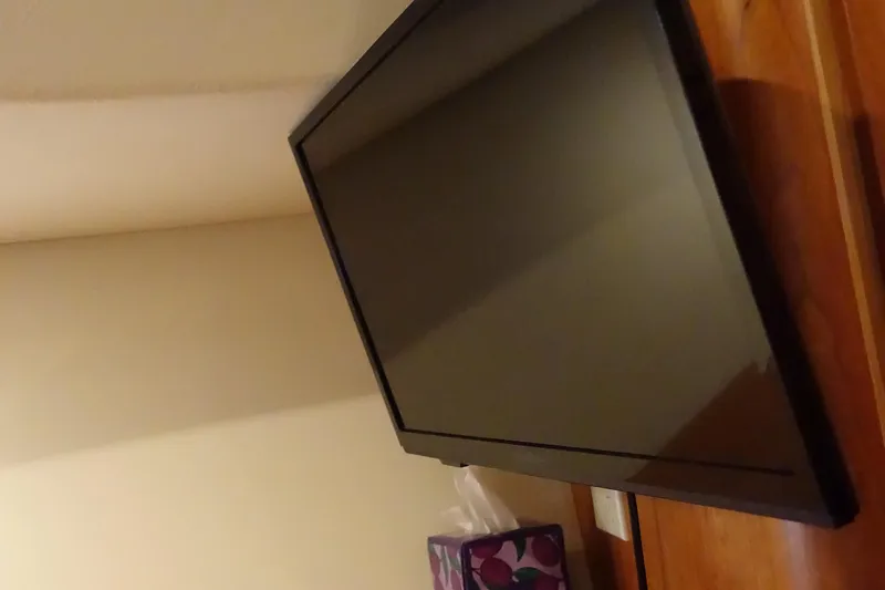  Yacht Photos Pics A flat-screen TV on a wooden stand beside a tissue box.