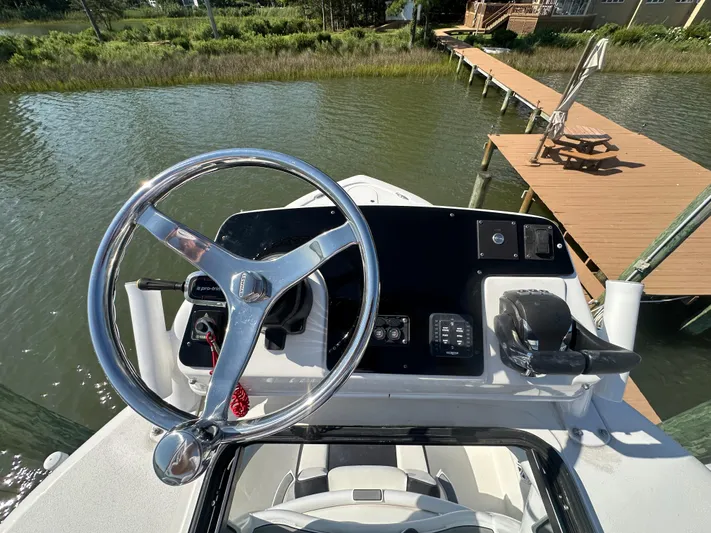  Yacht Photos Pics 2021 Tidewater 2700 Carolina Bay boat helm with steering wheel and controls by a dock.