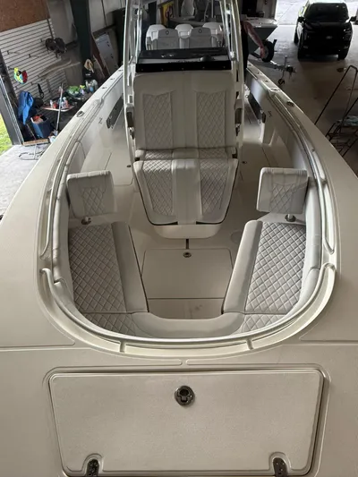  Yacht Photos Pics 2023 Fountain 34 CC boat interior with white cushioned seating in a garage.