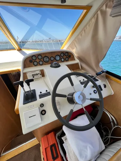Fantasea Yacht Photos Pics 1994 Navigator 43 Flybridge helm with steering wheel and control panel, docked by the water.