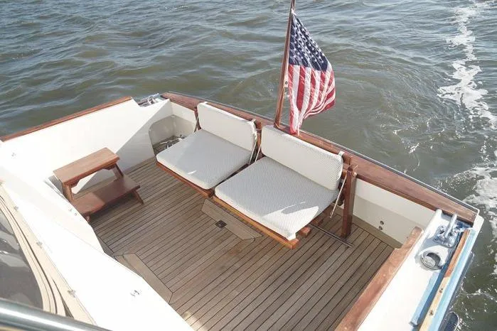 Faith Yacht Photos Pics 2003 Huckins Atlantic 44 boat deck with seating and American flag on water.