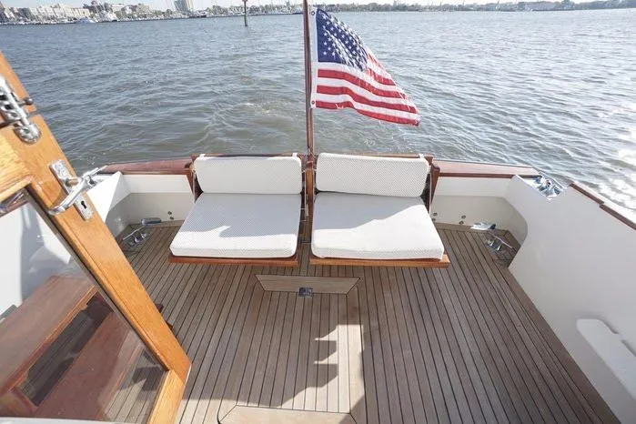 Faith Yacht Photos Pics 2003 Huckins Atlantic 44 yacht deck with seating and American flag on calm water.
