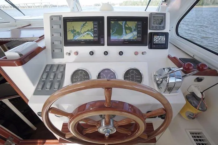 Faith Yacht Photos Pics Helm of 2003 Huckins Atlantic 44 yacht with navigation screens and wooden steering wheel.
